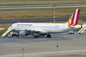 Ein Airbus A320-200 der Germanwings auf dem Frankfurter Flughafen, mit Fahrzeugen, Verkehrskegeln, Pfählen und Gras im Hintergrund.
