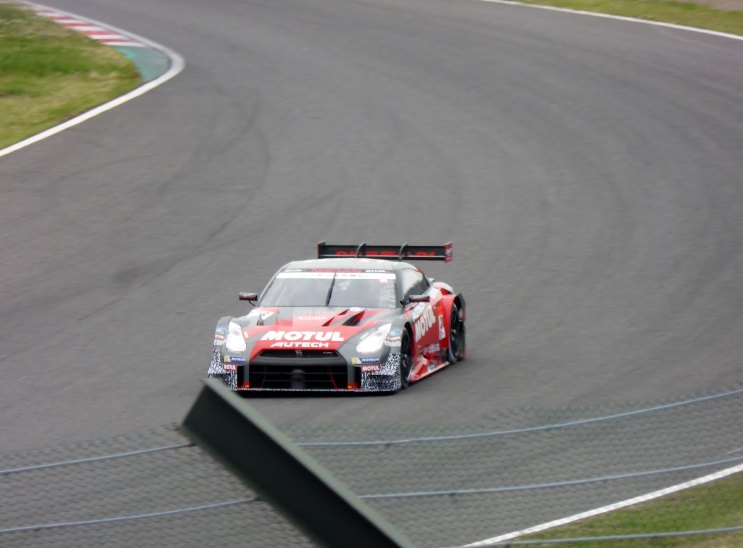 Nissan GT-R Nismo GT3 Rennauto auf der Nürburgring 24 Stunden Rennstrecke, umgeben von grünem Gras.