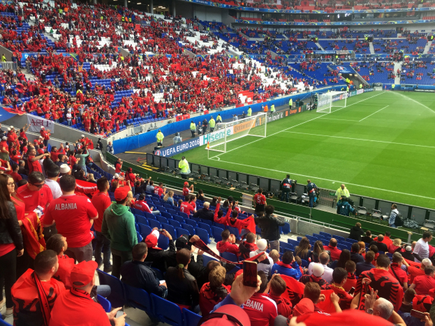Große Menschenmenge in einem Stadion bei einem Fußballspiel mit Bannern, einem Torpfosten und Deckenleuchten.