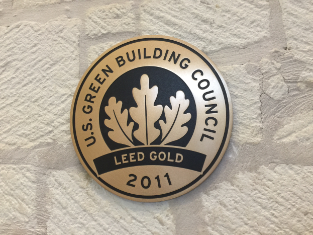 Das Logo der U.S. Green Building Council an der Seite eines Gebäudes, das ein Schild mit einem grünen Hintergrund und weißer Umrandung zeigt, mit den Worten 'Green Building Council' in fetter schwarzer Schrift, umgeben von einem Lorbeerkranz.