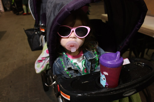 Kind auf einem Gehwagen sitzend auf der Straße positioniert.