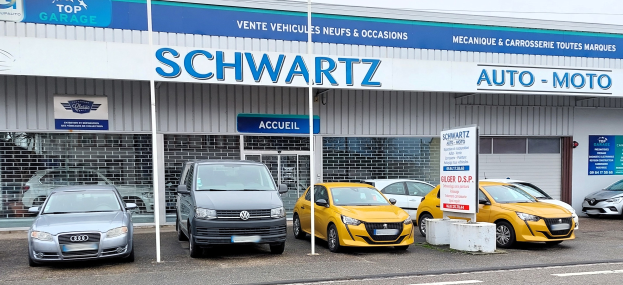 Außenansicht einer Schwartz Auto-Moto-Autohändler-Filiale mit Glaswänden und -türen, die parkende Autos und Texttafeln zeigt, unter einem sichtbaren Himmel.