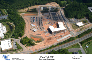 Luftaufnahme des Wake Tech RTP Campus Classrooms mit Gebäuden, Bäumen, Straßen, Fahrzeugen und Text mit einem Logo unten.