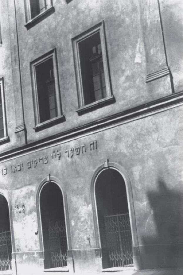 Schwarzes und weißes Foto eines Gebäudes in Jerusalem mit Fenstern, Türen und einem Metallzaun, das mutmaßlich eine jüdische Gemeinde-Synagoge ist.