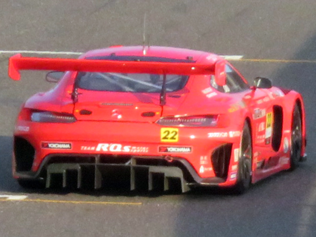 Roter Porsche 911 GTS Rennauto auf einer Rennstrecke mit aerodynamischem Design, großem Heckflügel und schwarzen Rädern.