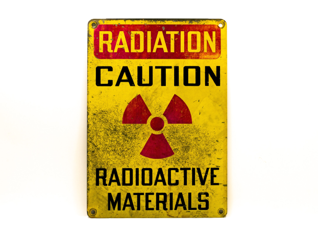 Gelbes Warnschild mit schwarzer "Strahlung Warnung"-Text und radioaktivem Symbol auf einem weißen Hintergrund.