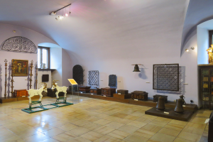 Ein Raum voller verschiedener Gegenstände wie Tierstatuen, Gegenstände auf dem Boden, Fotorahmen an der Wand, Fenster, Deckenlampen und andere Artefakte, wahrscheinlich im Museum des Heiligen Grabes.