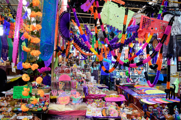 Ein belebter Markt mit verschiedenen zum Verkauf stehenden Gegenständen, darunter Spielzeuge und dekorative Gegenstände, unter einer mit Lichtern geschmückten Decke.