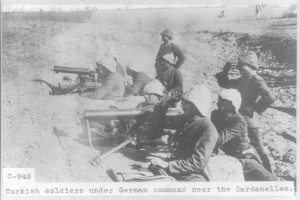 Eine Gruppe türkischer Soldaten unter deutschem Kommando, die Helme tragen und Waffen halten, steht auf einem Schwarz-Weiß-Foto mit Text unten.