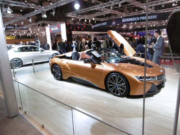 Schwarzer BMW i8 Roadster mit glänzender Lackierung und Chromakzenten, der auf der IAA in Frankfurt präsentiert wird und von formell gekleideten Besuchern umgeben ist.