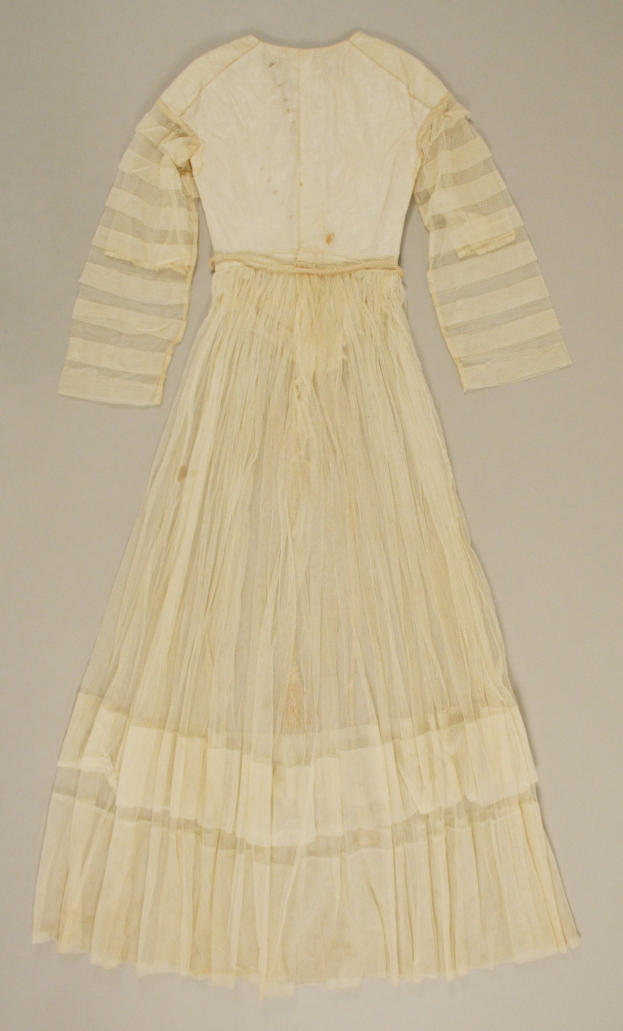 Weißes Spitzenkleid mit langen Ärmeln und einem voluminösen, gerafften Rock, der bis zum Boden reicht, auf einer weißen Oberfläche.