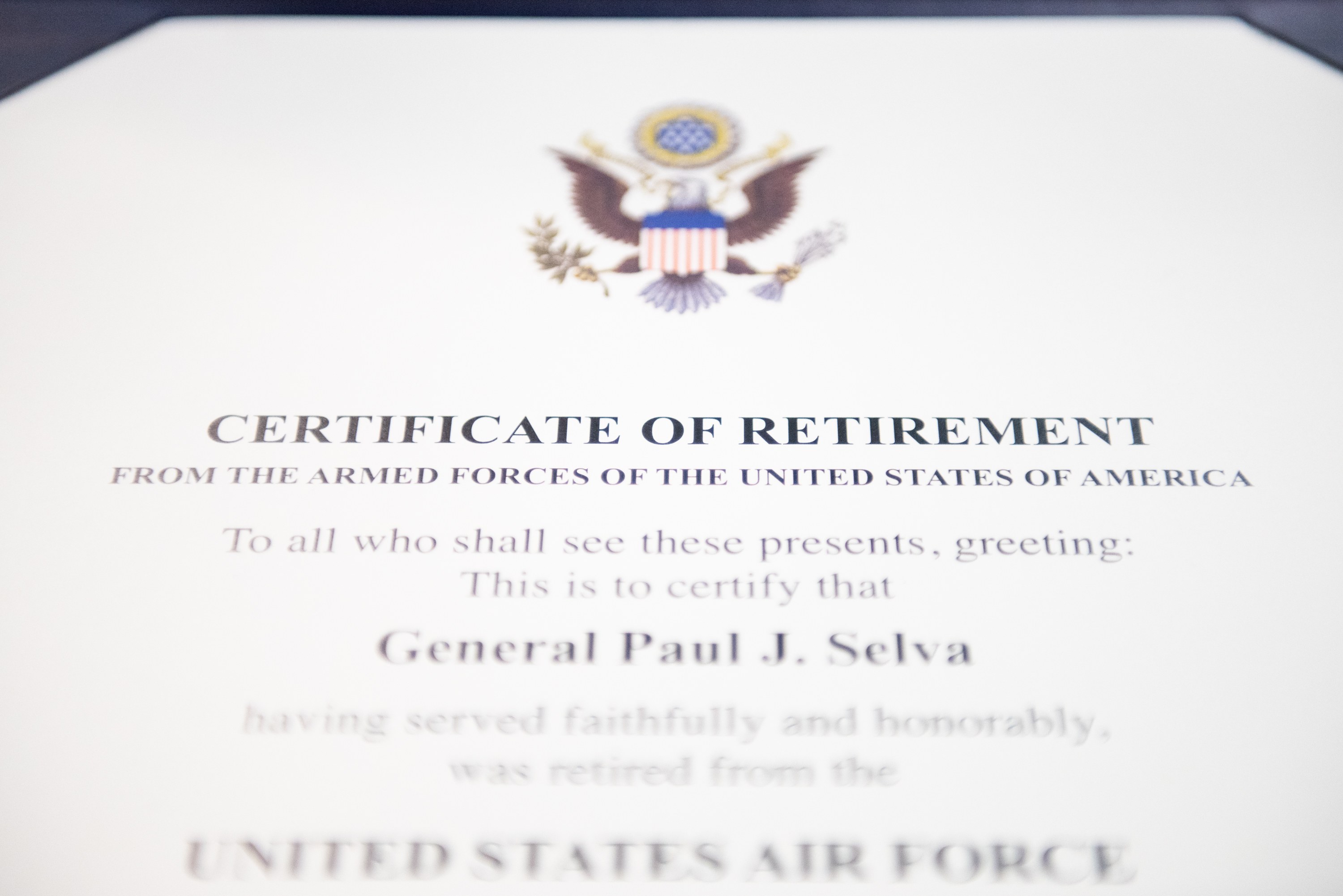 Rahmenurkunde für den Ruhestand der United States Air Force mit blauem Rand, die ein schwarzes Textfeld, ein zentrales Sternsymbol innerhalb eines Lorbeerkranzes und ein Banner mit der Aufschrift "Ruhestand" zeigt.